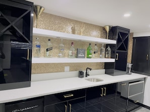 Enjoy cooking in this kitchen with a sink, black cabinets, and a refrigerator.