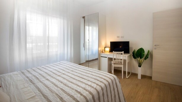 A hotel room with a bed, a desk with a chair, a television, and a door. - Convenient for motorway (Però exit) and for those using public transport ( Però) (Pero)