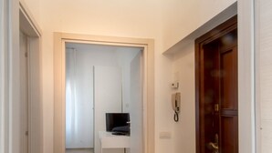 A hallway with wooden flooring, a white door on the left, and a wooden door on the right. - Convenient for motorway (Però exit) and for those using public transport ( Però) (Pero)