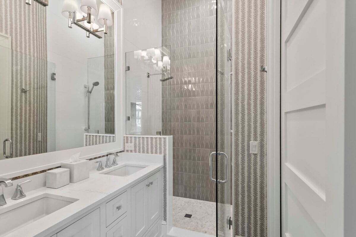 A modern bathroom with a glass-enclosed shower, a large mirror, and a double sink vanity.