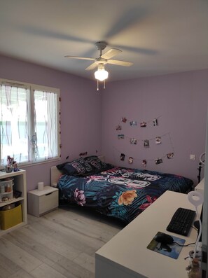 Une chambre à coucher avec un lit, un bureau et un ventilateur de plafond.