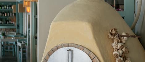 Un horno de ladrillo con una chimenea, una guirnalda de ajos colgante y una puerta color aguamarina.