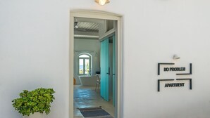 A doorway leading to a bathroom with a bathtub, a sink, and a mirror. There is a potted plant beside the door. - Samaria by the Sea (Sfakia)