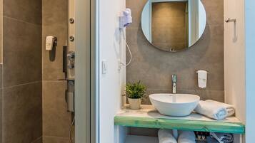 Un baño moderno con un espejo grande, un lavabo y una ducha.