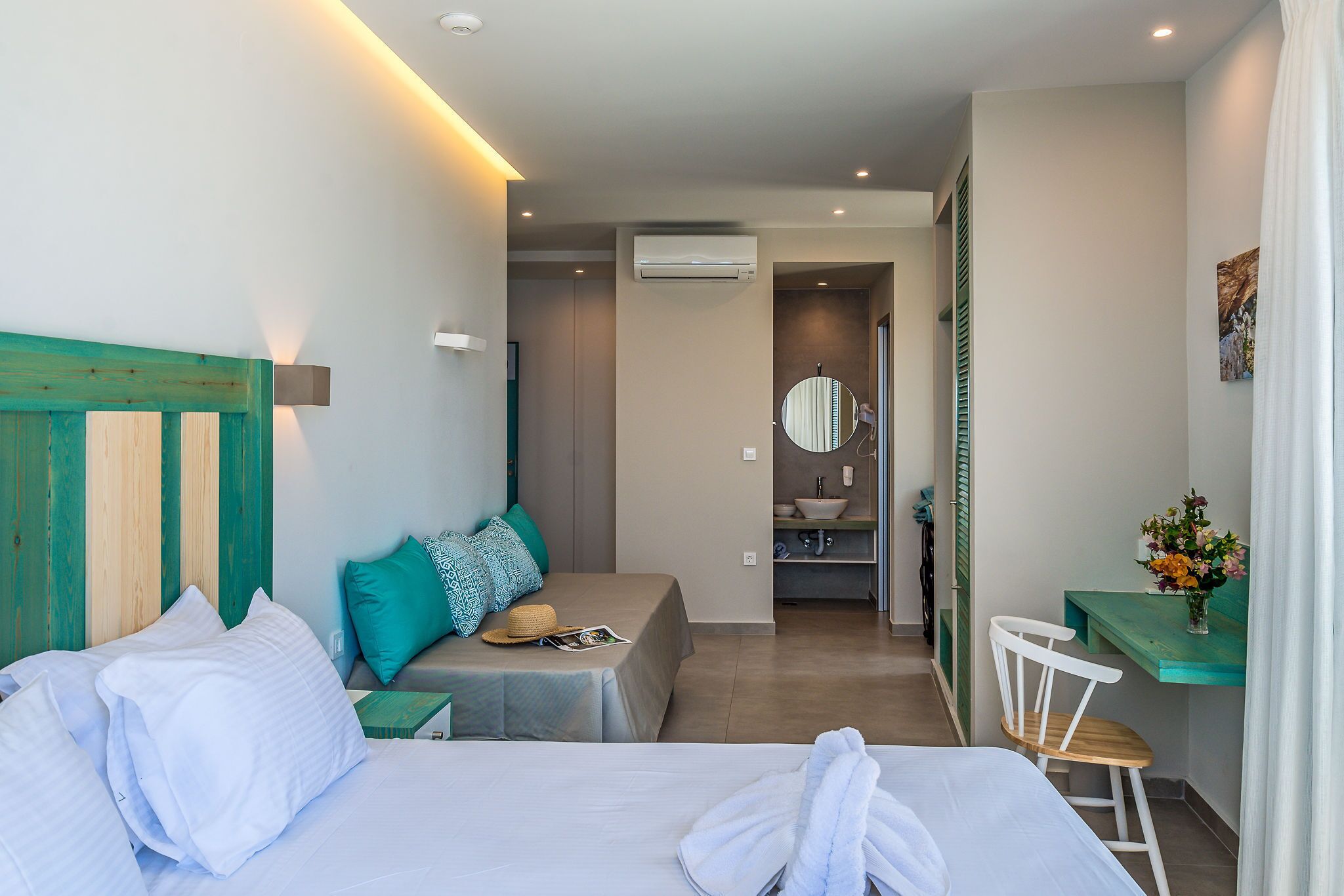 Ein Hotelzimmer mit zwei Betten, einem Schreibtisch, einem Stuhl, einem Badezimmer und einer kleinen Sitzecke.