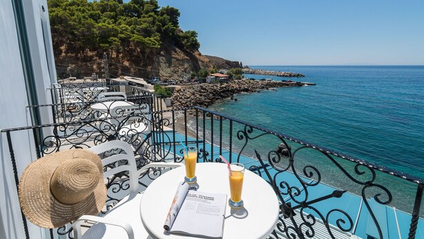 A balcony with a view of the sea, a white chair, a straw hat, and two drinks on a table. - Samaria by the Sea (Sfakia)