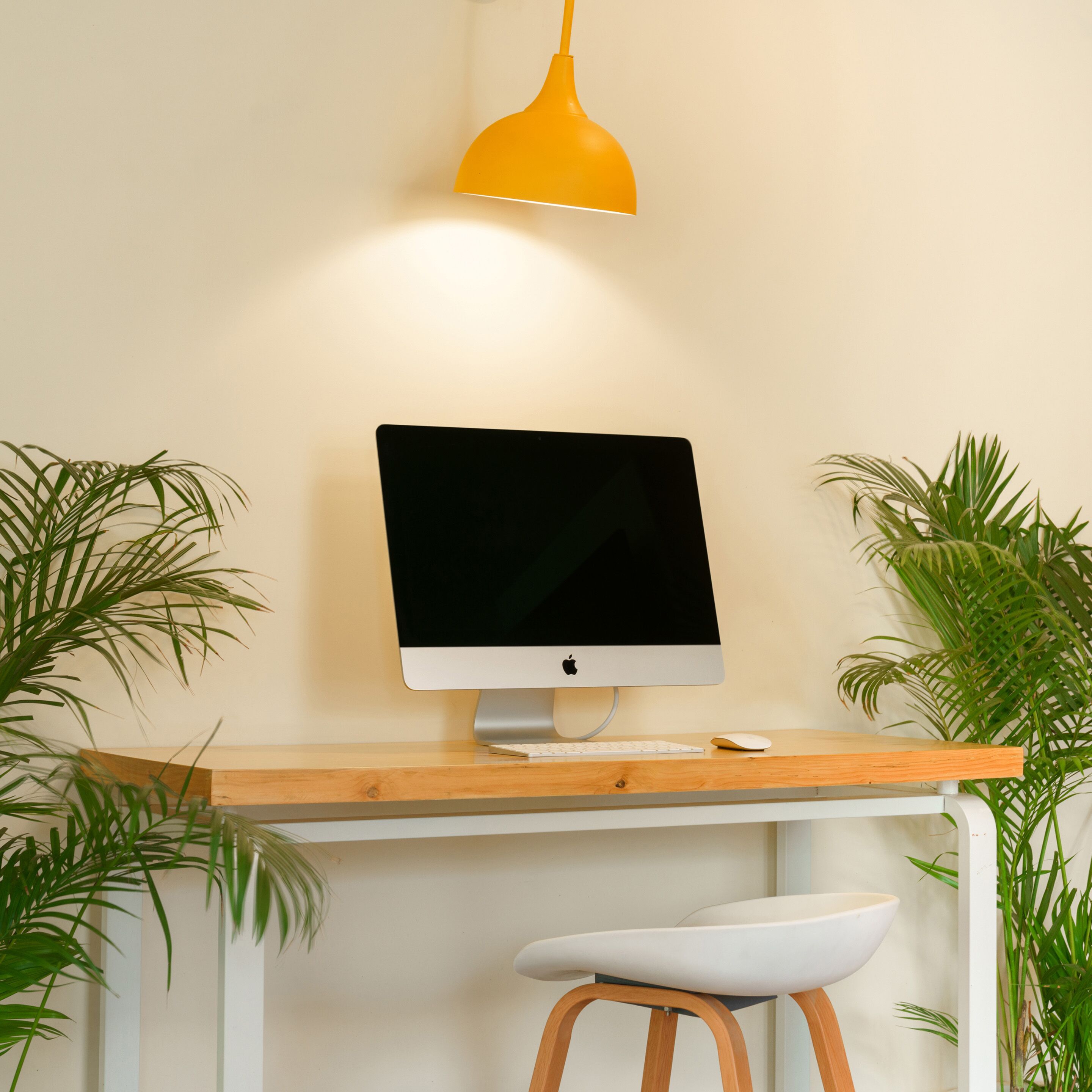 Un espacio de trabajo moderno con un monitor de ordenador, teclado y taburete.
