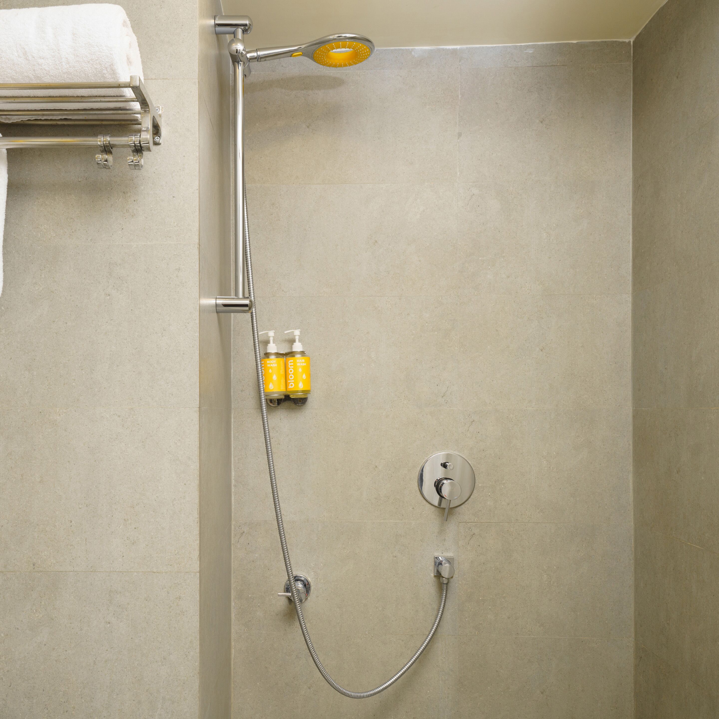 Een douche met douchekop en handdouche, en een bedieningskraan aan de muur.