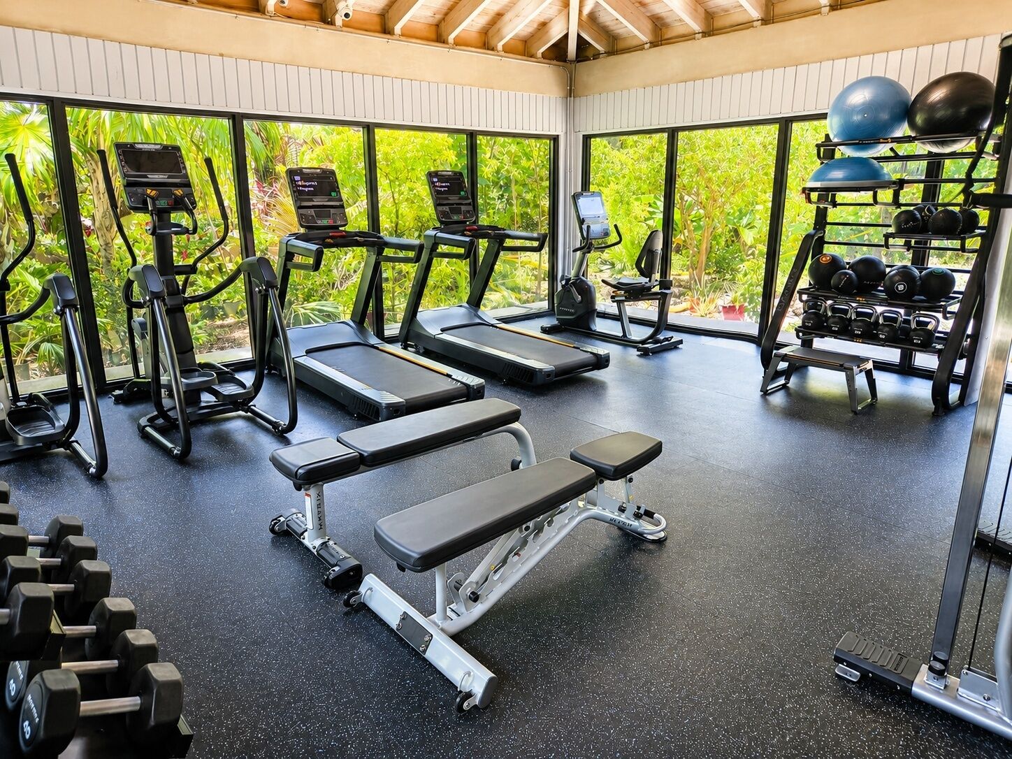 A gym with treadmills, weight benches, and a rack of dumbbells.