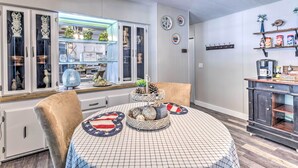 Zona pranzo con tavolo rotondo, sedie e una cucina sullo sfondo.
