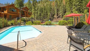 A pool area with lounge chairs and a view of a forested mountain. - Updated Condo with River Views! Near Alpine! (Alpine Meadows)