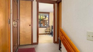 A staircase with wooden handrails, a red mat at the bottom, and a door leading to a room with a window. - Updated Condo with River Views! Near Alpine! (Alpine Meadows)
