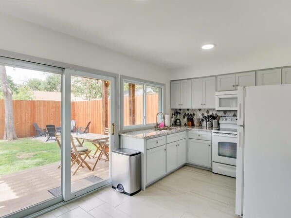 Enjoy cooking and entertaining in this well-lit kitchen with stainless steel appliances and large windows opening to a backyard patio.