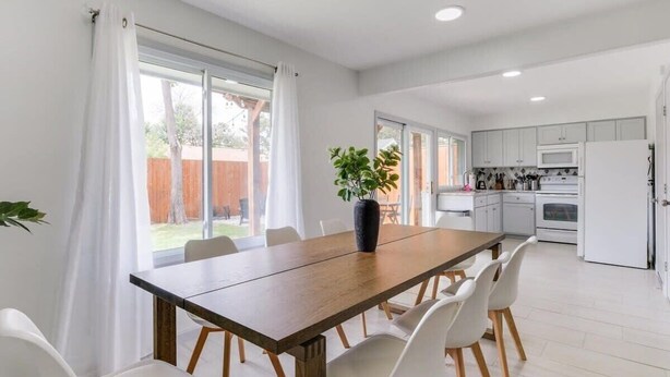 Una cocina moderna con armarios blancos, una mesa de comedor de madera y una planta en maceta.