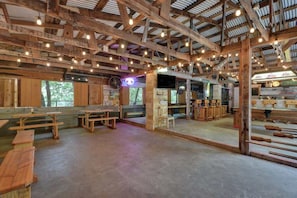Un interior rústico con vigas de madera, mesas y bancos, junto con una variedad de herramientas y equipos.