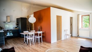 Une cuisine moderne avec un coin repas, un plancher en bois et une grande fenêtre.