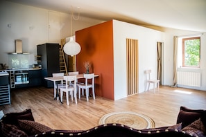 Een moderne keuken met een eethoek, houten vloeren en een groot raam.