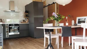 Une cuisine moderne équipée d’un four encastré, d’un réfrigérateur et d’un coin repas avec une table et des chaises.