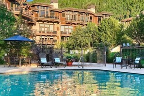 A pool area with lounge chairs and a view of a large building with multiple balconies.