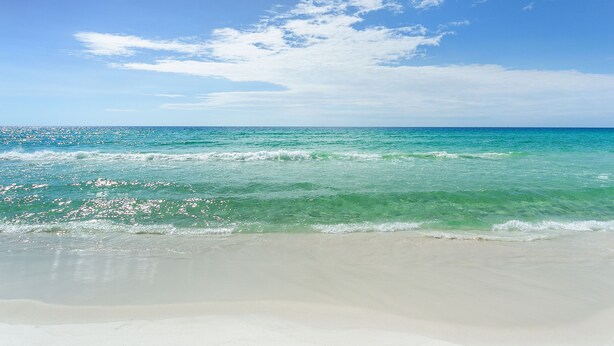 A beach with clear turquoise water and a sandy shore under a bright blue sky. - Extra Large Balcony Overlooking the Beach in Destin w/ Resort Amenities! (Destin)