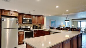 A modern kitchen with stainless steel appliances, wooden cabinets, and a central island. - Extra Large Balcony Overlooking the Beach in Destin w/ Resort Amenities! (Destin)