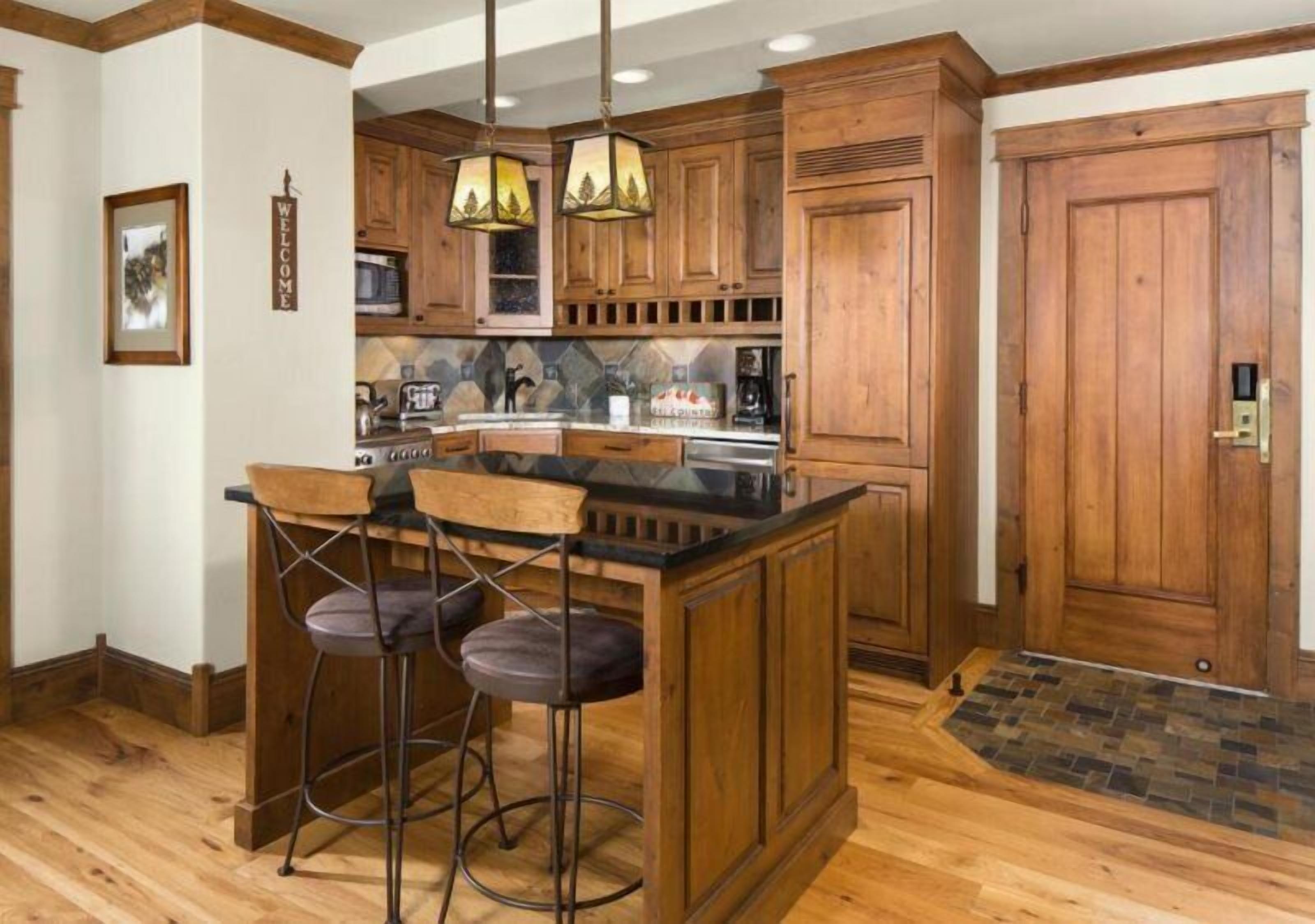A kitchen with wooden cabinets, a bar area with stools, and a stone backsplash.