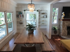 Cozy room with a dining table, large windows, and a stone fireplace.