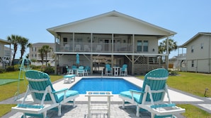 A two-story house with a swimming pool, outdoor seating, and a covered patio area. - Kick's Kids - Channelfront in Garden City Beach! (Garden City Beach)