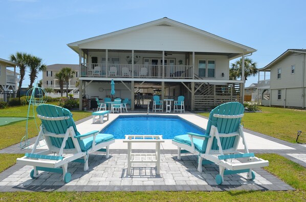 A two-story house with a swimming pool, outdoor seating, and a covered patio area. - Kick's Kids - Channelfront in Garden City Beach! (Garden City Beach)