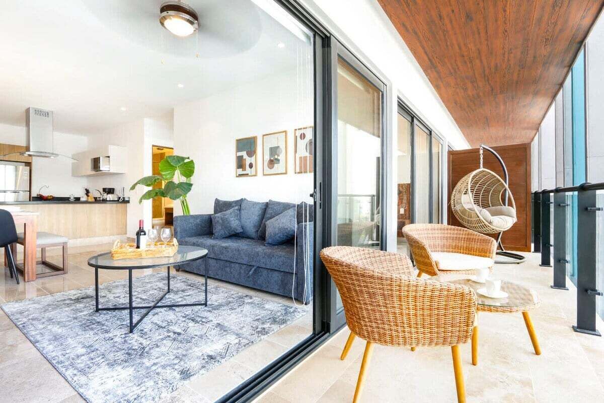 A modern living room with a sofa, coffee table, and wicker chairs.