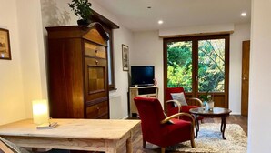 Un salon avec une table en bois, un fauteuil rouge et un téléviseur.