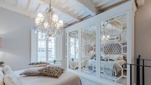 A bedroom with a large bed, a chandelier, and a view through a geometric-patterned door. - Luxury Apartment with Private Garden inside Lucca (Lucca)