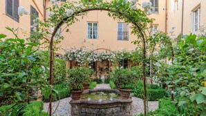 A courtyard with a fountain, surrounded by lush greenery and flowering plants. - Luxury Apartment with Private Garden inside Lucca (Lucca)