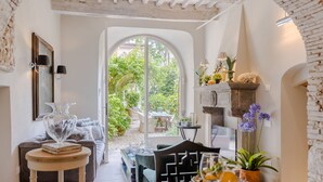 A cozy interior with a dining area, a fireplace, and a view of a garden through an arched doorway. - Luxury Apartment with Private Garden inside Lucca (Lucca)