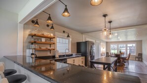 A modern kitchen with a large island, built-in shelves, and pendant lighting. - 3/2 home 20 minutes from Glacier National Park, Sleeps 8! (Columbia Falls)
