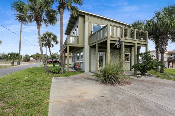 A two-story building with a balcony, surrounded by palm trees and a grassy area. - 175 Steps from the Beach, Sweeping Views, Ground Floor (Mexico Beach)