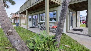 A building with a covered outdoor seating area, a door with a mat, and a car parked outside. - 175 Steps from the Beach, Sweeping Views, Ground Floor (Mexico Beach)