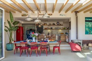 A spacious dining area with a wooden ceiling, red chairs, and a table set for four.
