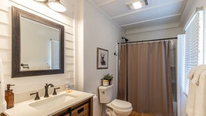 A bathroom with a white sink, dark faucets, a toilet, and a shower curtain.