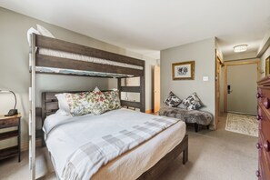 A bedroom with a bunk bed, a desk, a chair, a dresser, and a framed picture on the wall.