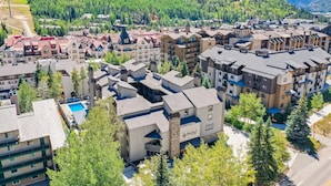 A residential area with modern multi-story buildings, a swimming pool, and a mountainous backdrop. - Lockoff room in heart of Lionshead Village W208B (Vail)