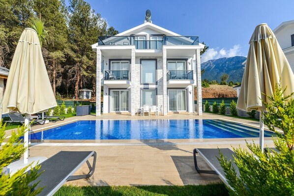 Ein modernes, zweistöckiges Gebäude mit Pool vor der Fassade.