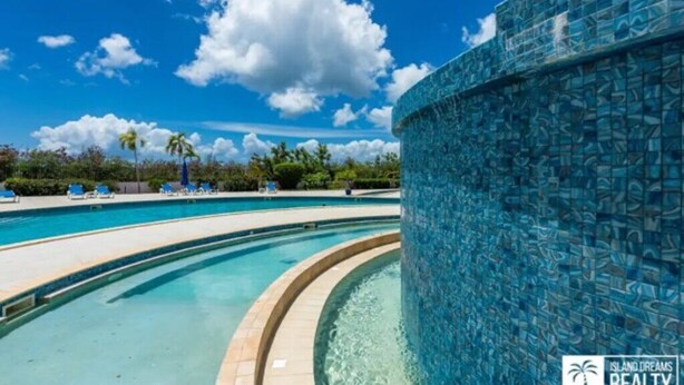 A pool area with clear blue water, a tiled wall, and lounge chairs. - A Caribbean Dream Vacation w/ Breathtaking Views
 (Sint Maarten)