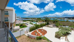 A modern residential complex with a pool, landscaped gardens, and a view of the ocean and city skyline. - A Caribbean Dream Vacation w/ Breathtaking Views
 (Sint Maarten)