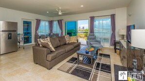 A modern living room with a sofa, coffee table, and a view of the city through large windows. - A Caribbean Dream Vacation w/ Breathtaking Views
 (Sint Maarten)