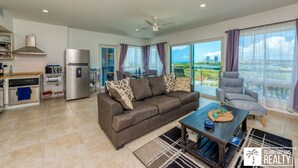 A modern living room with a sofa, coffee table, and a view of the ocean. - A Caribbean Dream Vacation w/ Breathtaking Views
 (Sint Maarten)