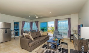 A modern living room with a sofa, coffee table, and a view of the city through large windows.
