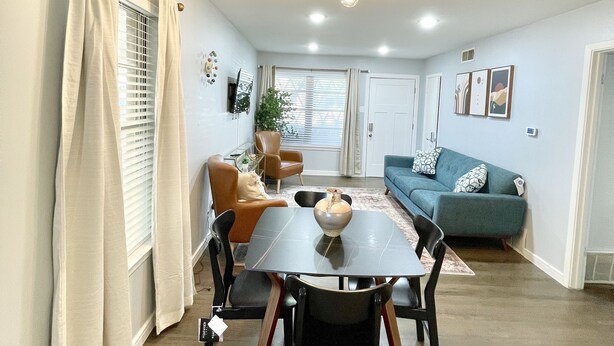 A dining area with a table and chairs, a sofa, and a cat.