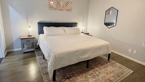 A bedroom with a bed, a ceiling fan, a nightstand, a rug, and wall art.