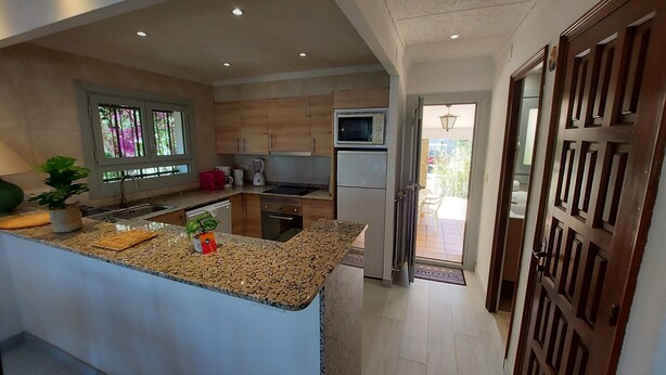 A modern kitchen with granite countertops, wooden cabinets, and a built-in microwave. - Spacious villa close to the beach and the forest (L'Escala)